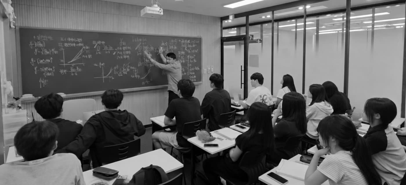 정규수업 중 칠판 앞에서 개념을 설명하는 강사와 학생들