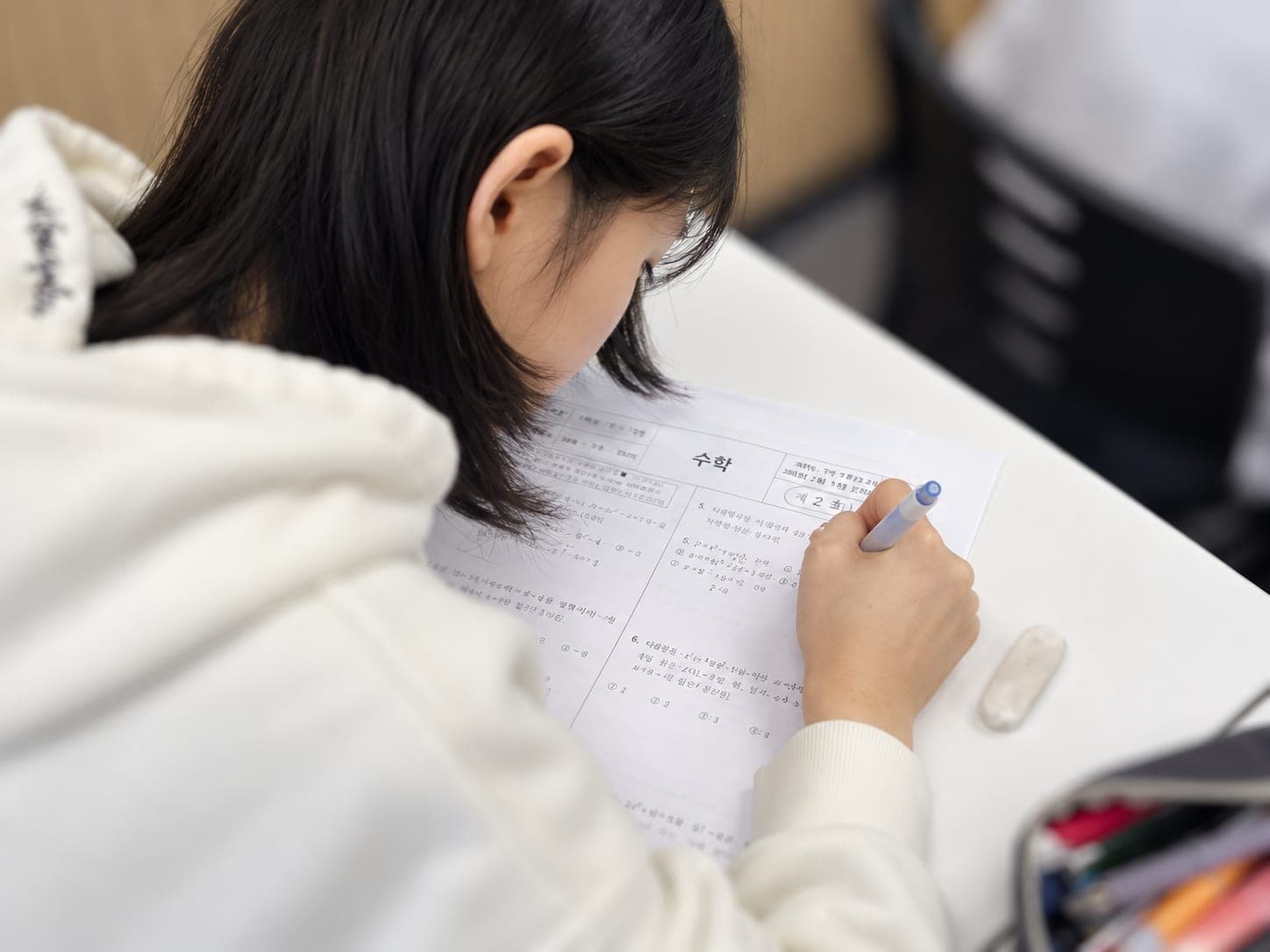 수학 시험지에 풀이를 적고 있는 학생
